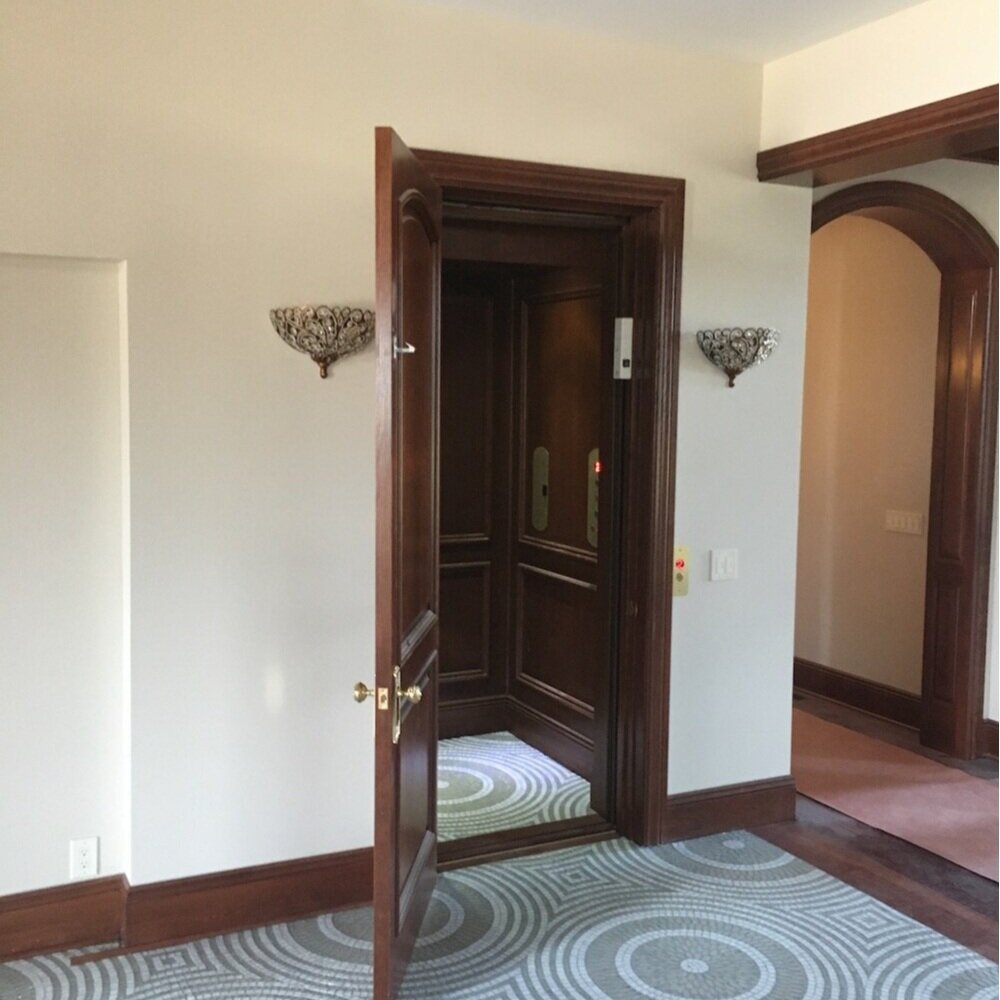 Residential Home Elevator with wood paneling and wooden door. Arrow Lift