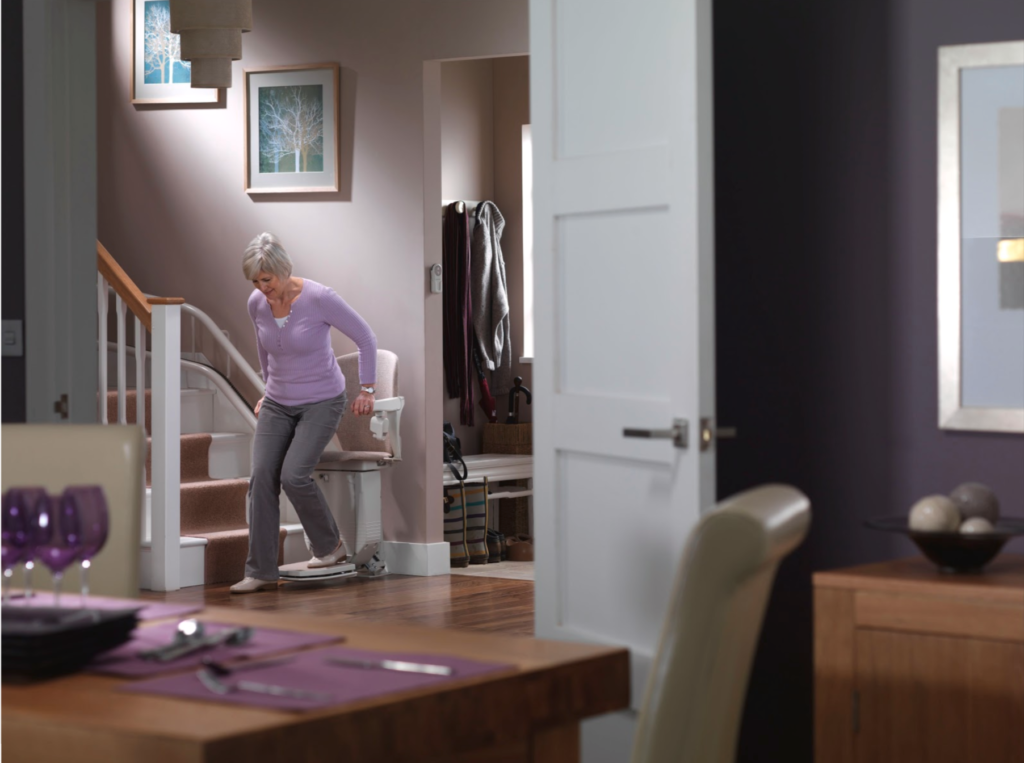Woman in home getting off of stairlift. Handicap lifts for home options. 