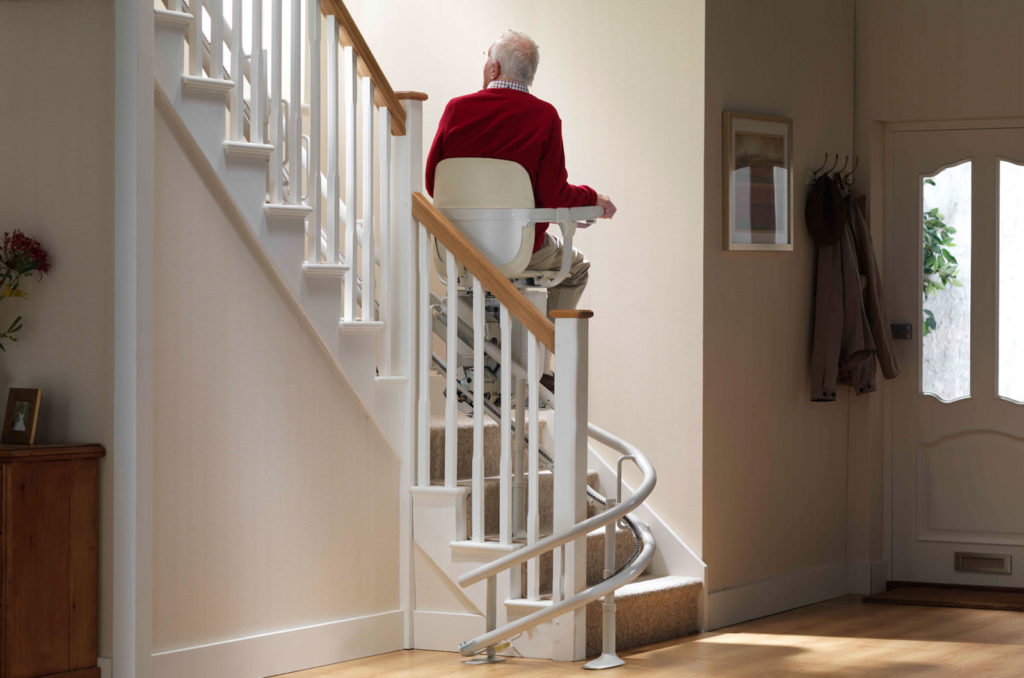 Elderly man using a stair lift on his curved stairs