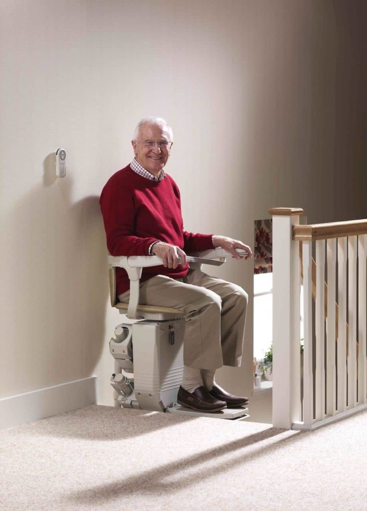 Person sitting in stair lift at the top of the stairs 