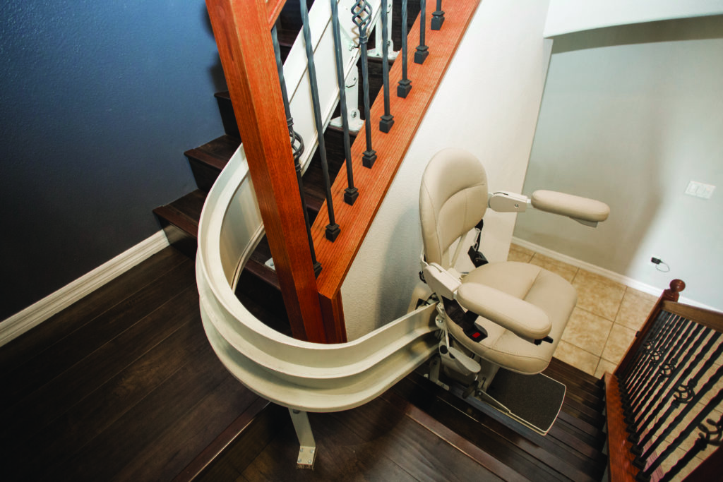 Image of a stair lift traveling up a curved rail to top landing | Arrow Lift