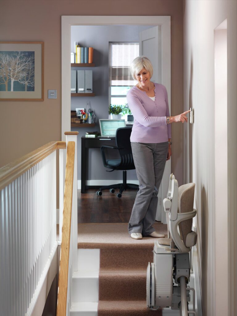 Woman calling a stair lift chair to the top landing