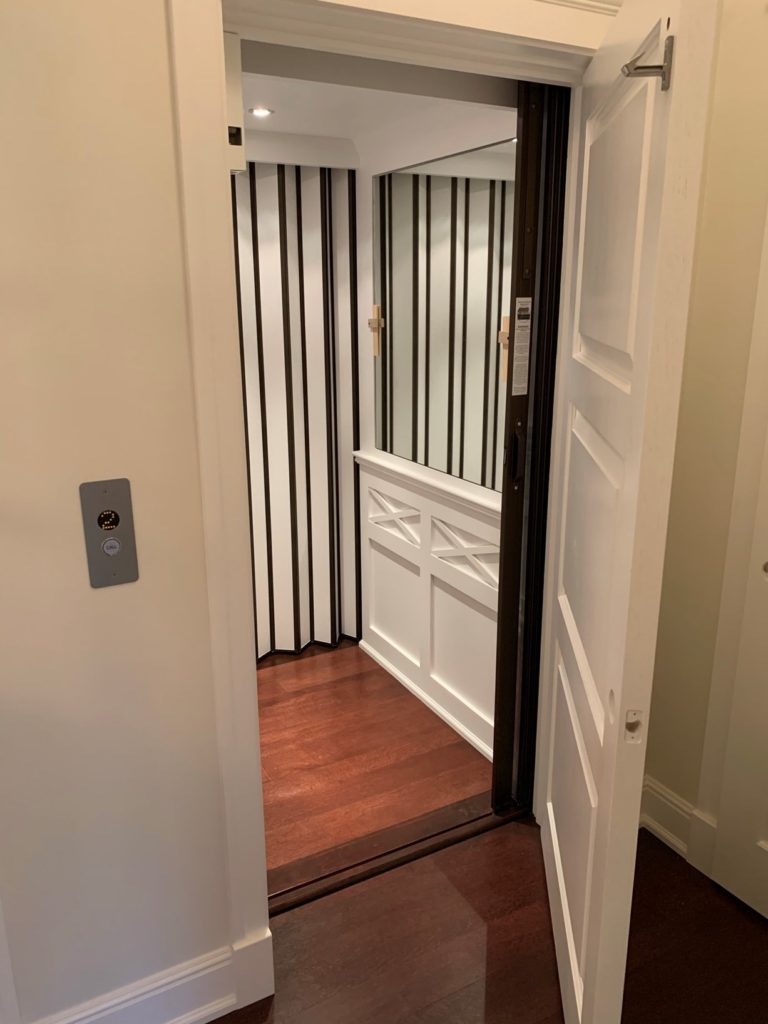 White paneled home elevator with large mirror
