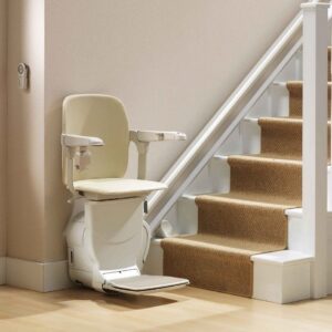 Stannah Siena stair lift at base of stairs with seat and arms down. Arrow Lift