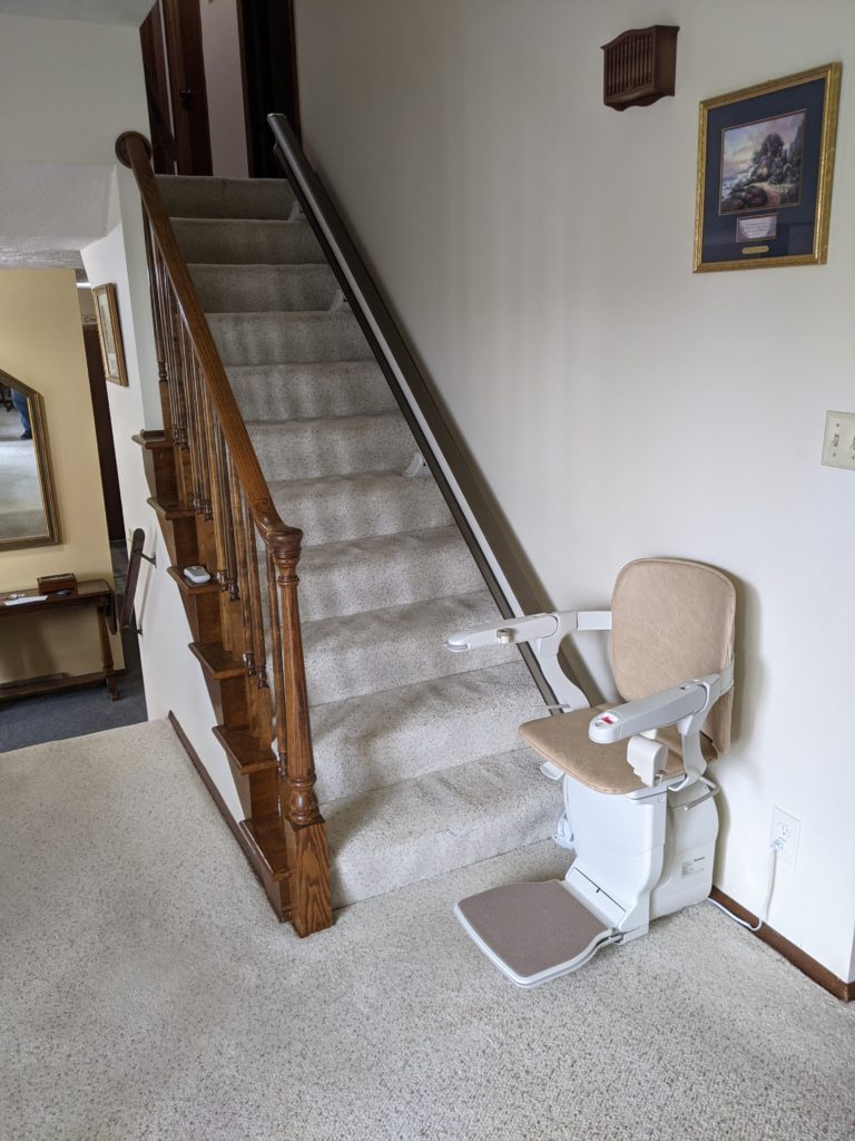Straight stairglide at base of stairs with chair folded down.