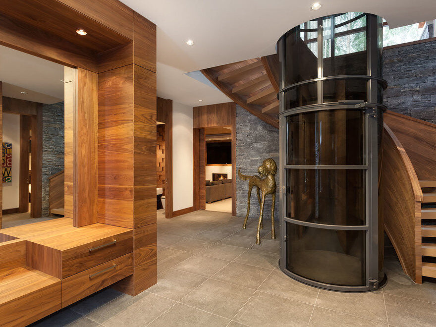 Pneumatic Elevator in home entrance beside large wooden spiral staircase