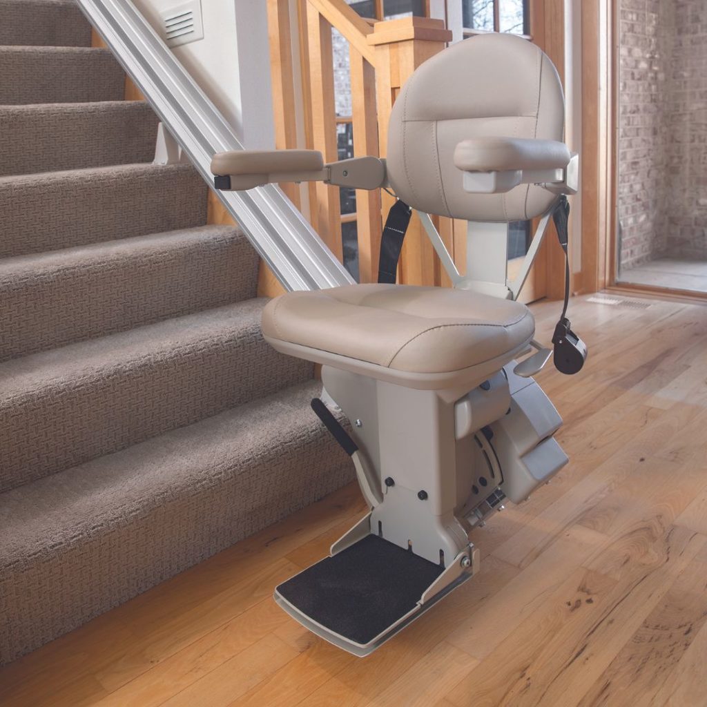Bruno Elite Stair Lift at base of stairs with seat and arms down. Arrow Lift