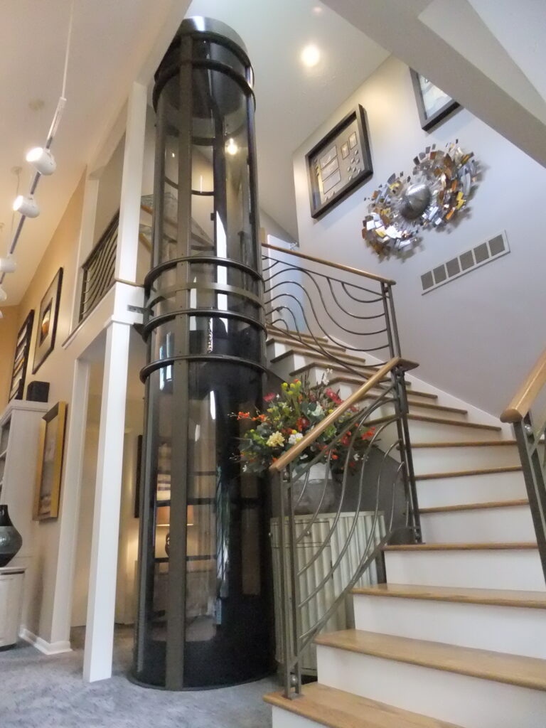 2-stroy foyer with custom Pneumatic Elevator with an exit on each landing beside a large curved staircase.