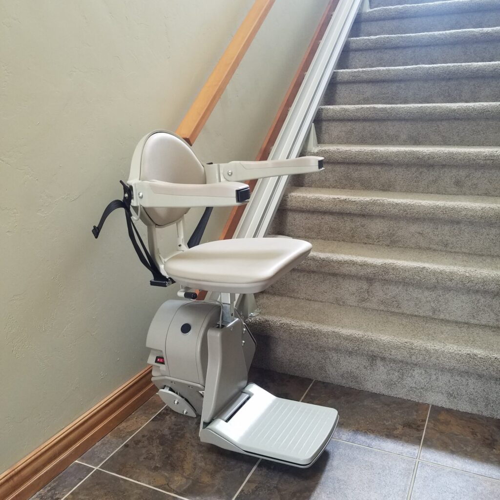 Used stair lift at the base of staircase with arms, chair and foot rest in the down position.