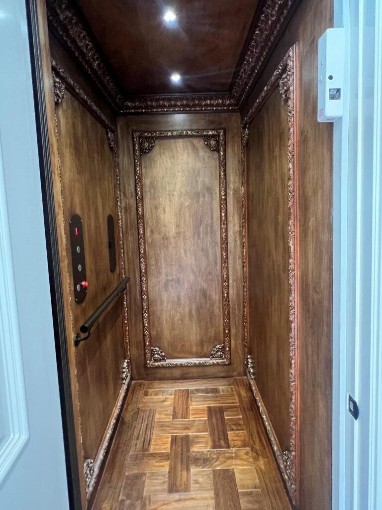 Wooden elevator interior featuring parquet floor and intricately designed trim