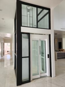 Modern Home Elevator in Glass Shaft at bottom landing with doors closed