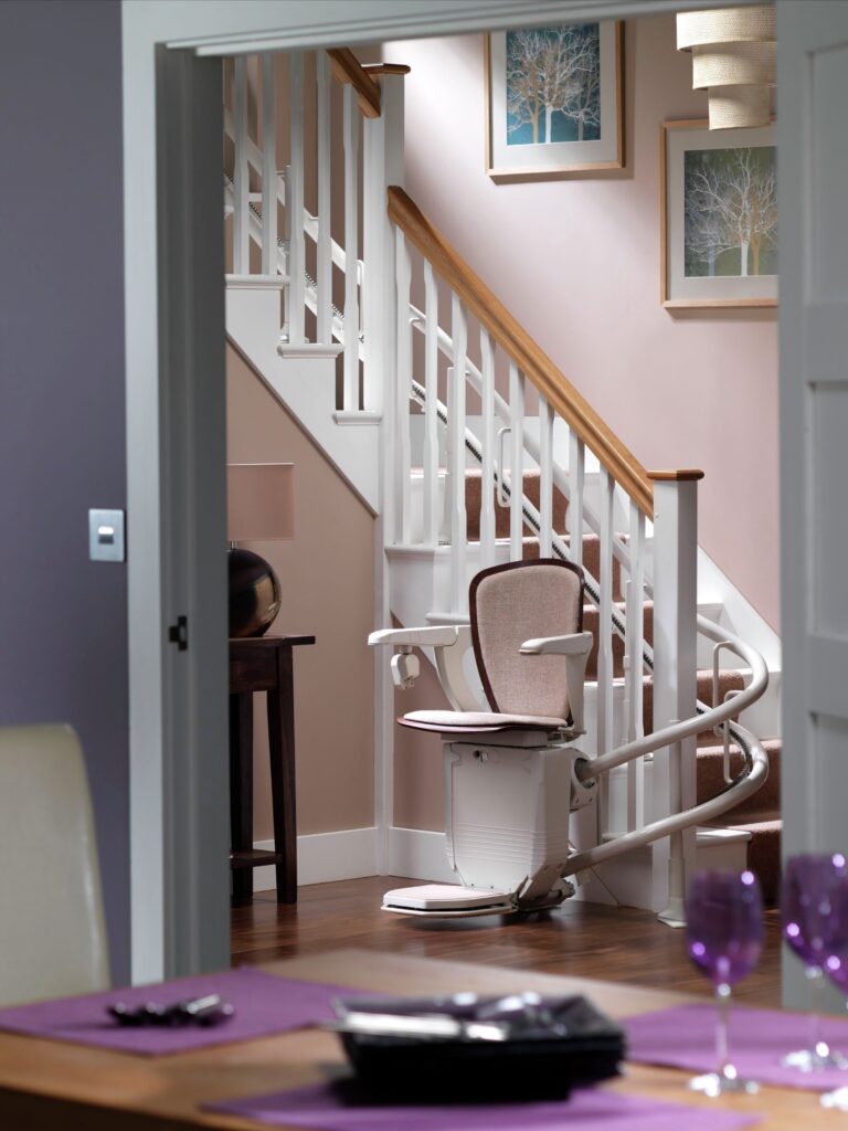 Image of curved stair lift parked at the base of staircase. Seen through an open doorway.