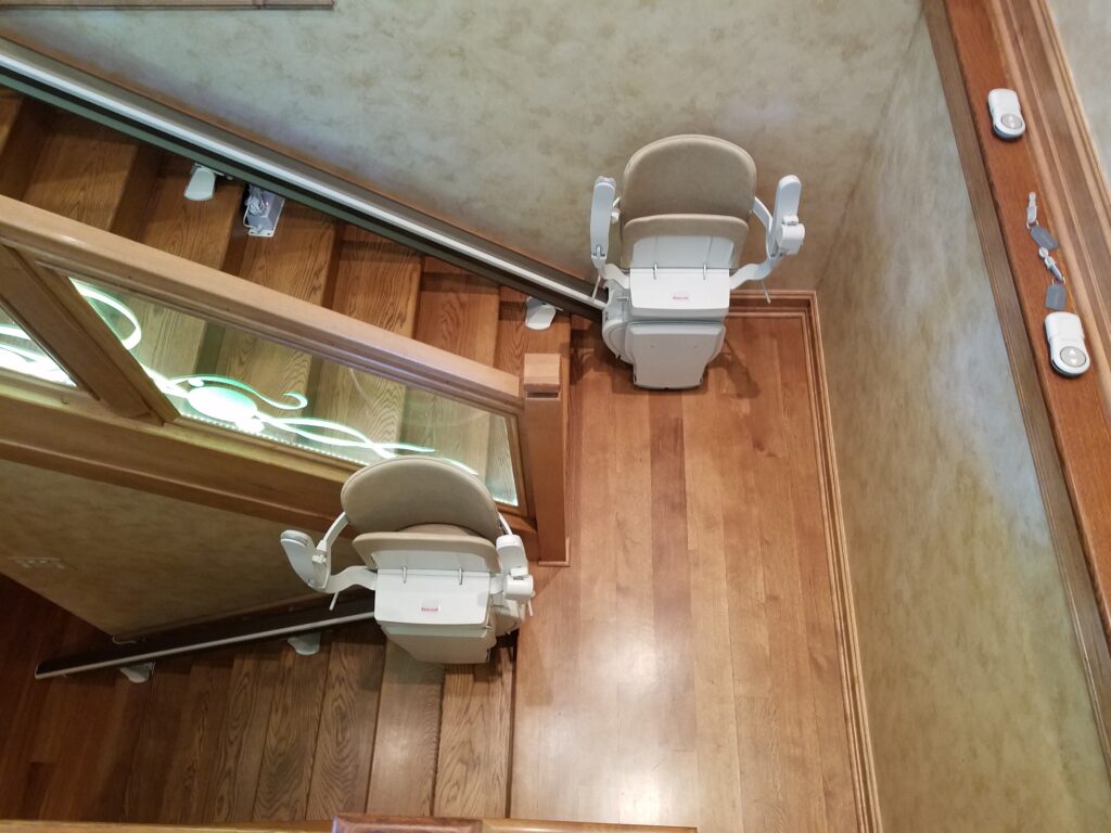 Two straight stairway chair lifts accommodate a set of stairs with a landing to create accessible stairs for those who need mobility assistance.