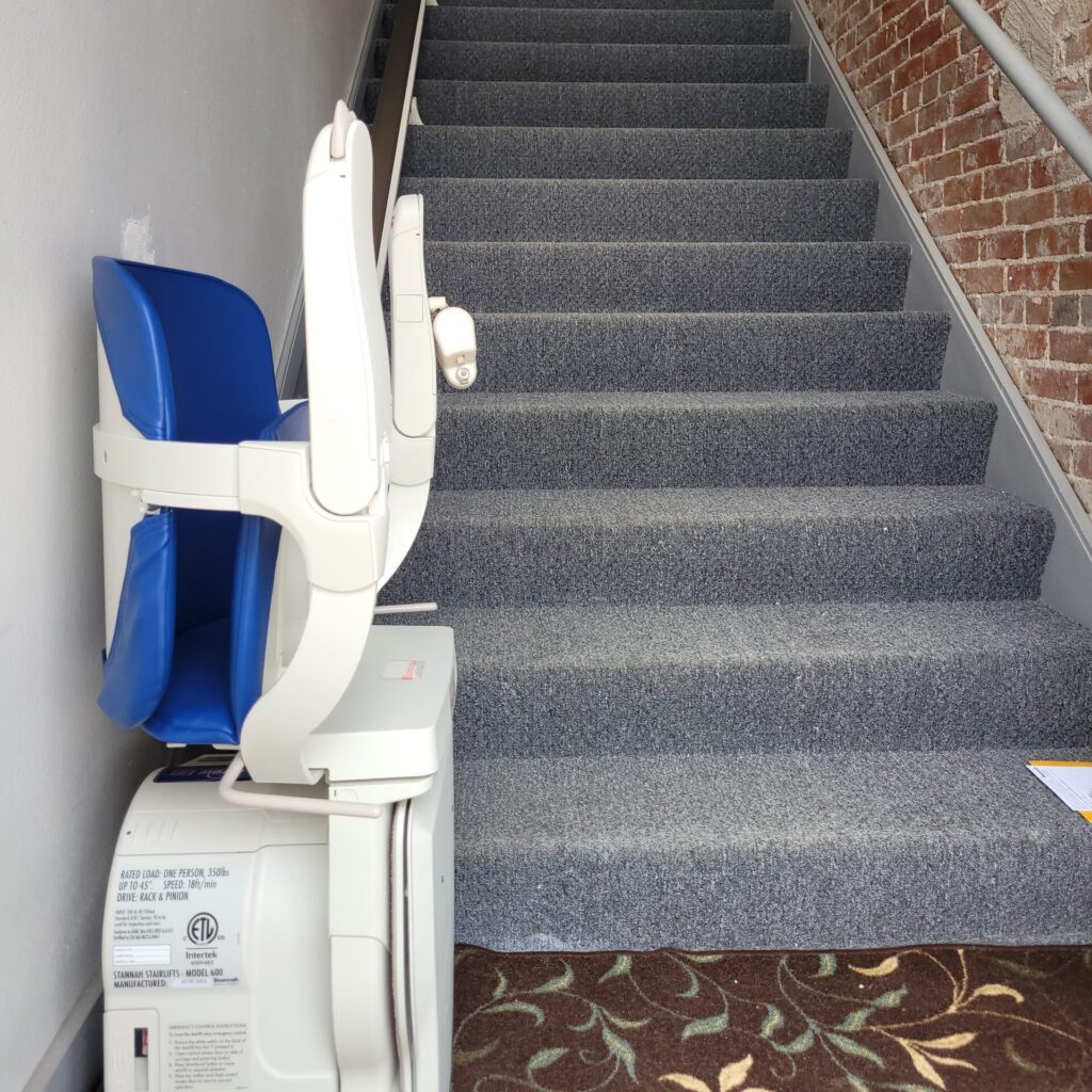 Image of a stair lift folded up at the base of a staircase