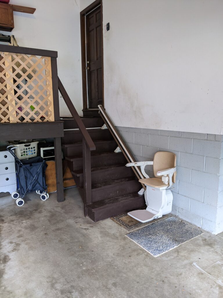 Stair lift in a garage at the base of the stairway