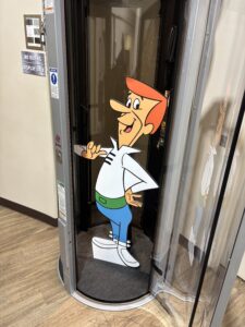 George Jetson cardboard cutout placed inside the demo vacuum elevator at Arrow Lift's showroom in Beachwood, Ohio