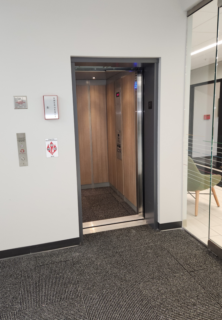 Commercial LULA elevator with modern wood panel interior and open doors in professional office building
